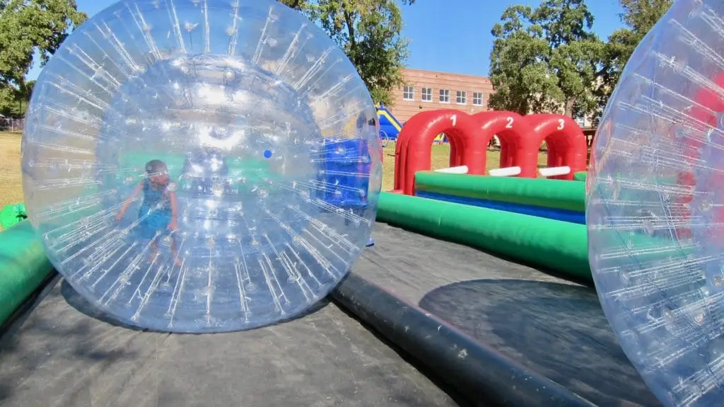 Students Walk Inside Giant Inflatable Balls Donated by Vehicle Safety Lawyer Todd Tracy for Medano Elementary School Carnival in Dallas